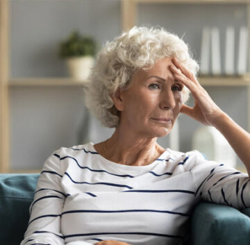 Image depicting a dimly lit room with an elderly person exhibiting signs of agitation or confusion during the evening, representing sun downing behavior in individuals with dementia.